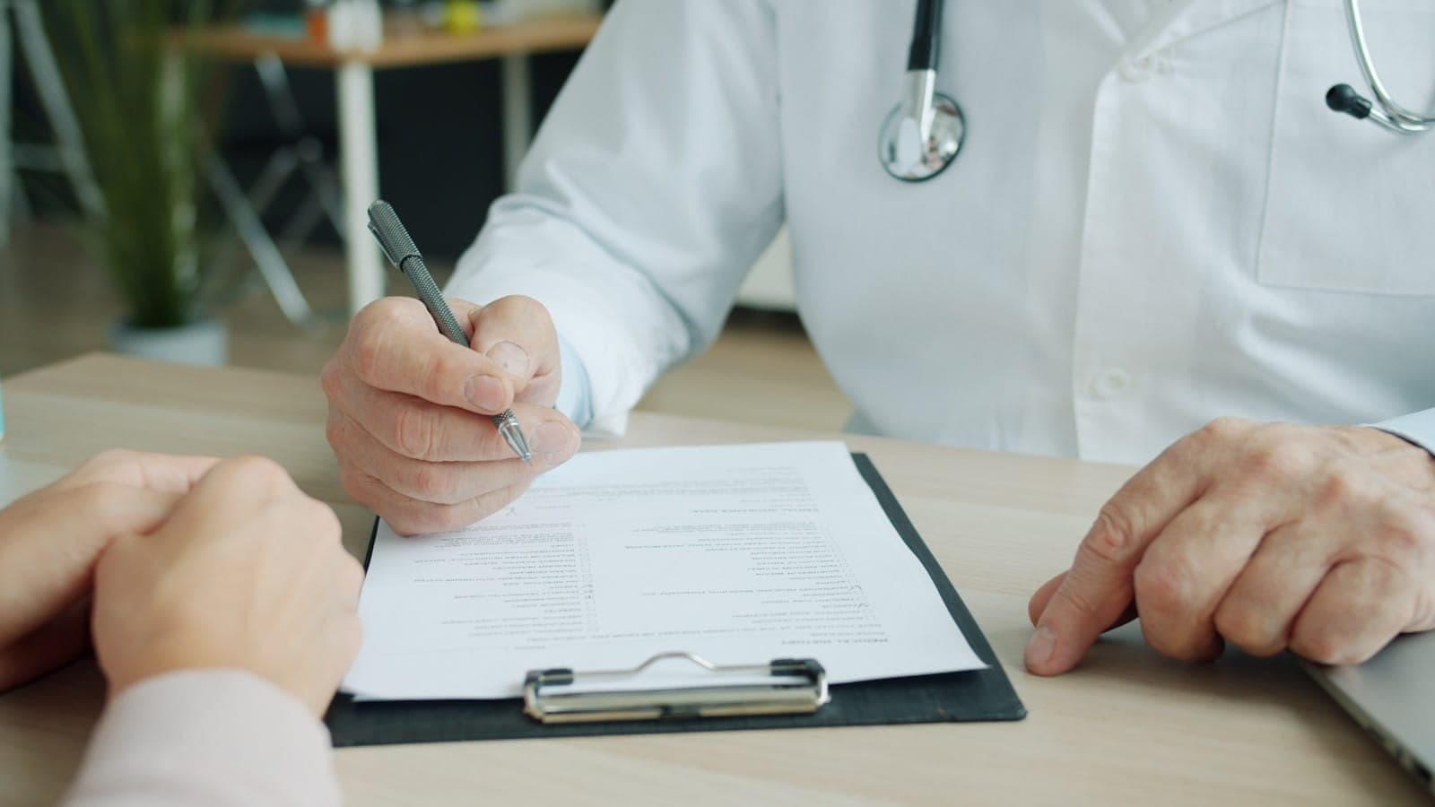 Doctor in a white coat filling out a form on a clipboard