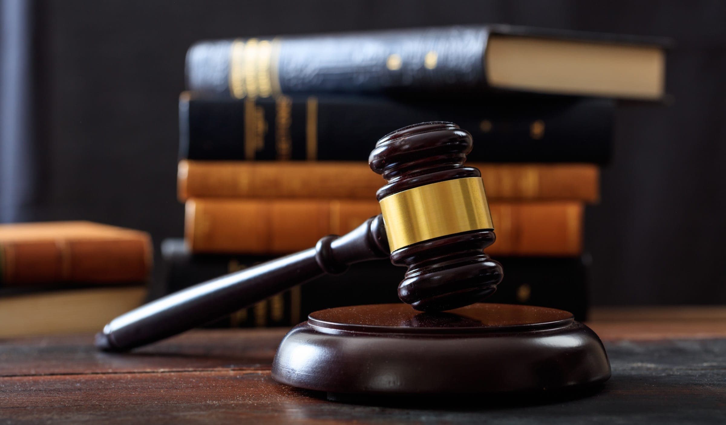 Wooden gavel on its sound block in front of a stack of leather bound law books
